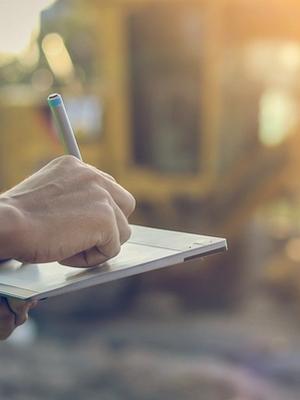A close up on a hand writing on a clipboard at a health and safety inspection on an agricultural site