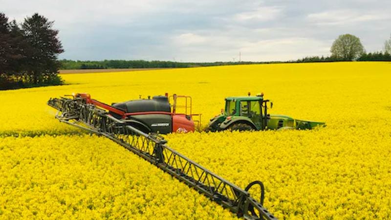 A tractor sprays a field of osr